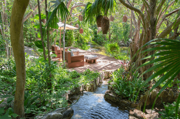 two lounge chairs sit on dock overlooking canal in jungle